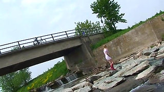 Blonde pissing outside in a river