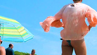 Playful nude beach girl caught on camera tanning